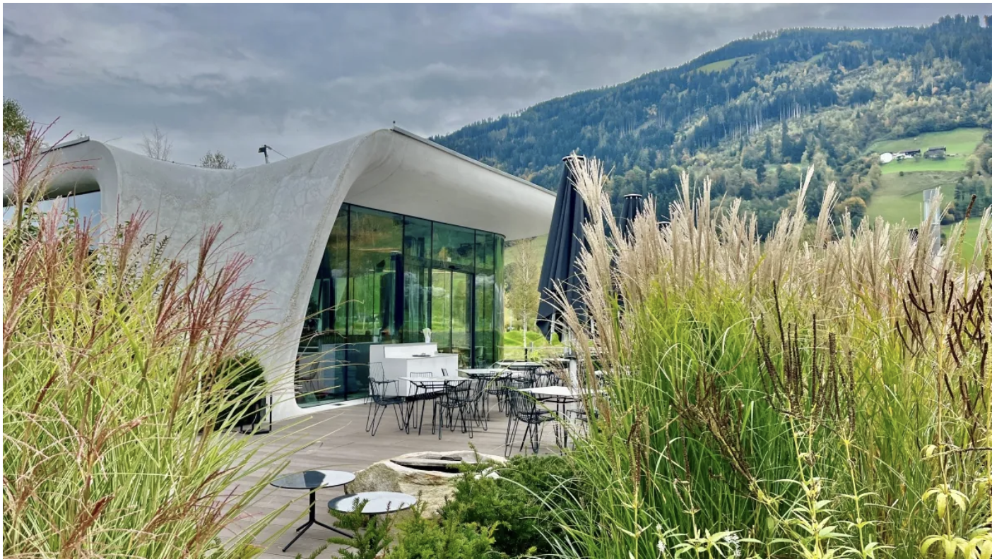 Sculptural restaurant terrace surrounded by grasses and mountain scenery